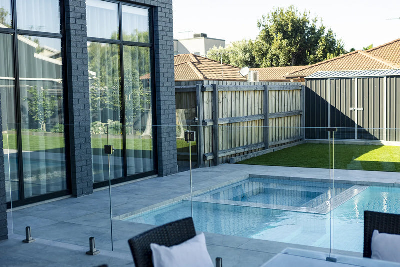 Glass mosaic tiled concrete pool against charcoal brick home in Altona by Fine Art Pools